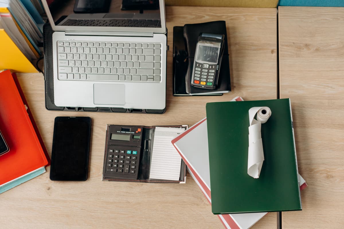 Close-up of an open textbook, a laptop, and neatly arranged stationery on a wooden desk.